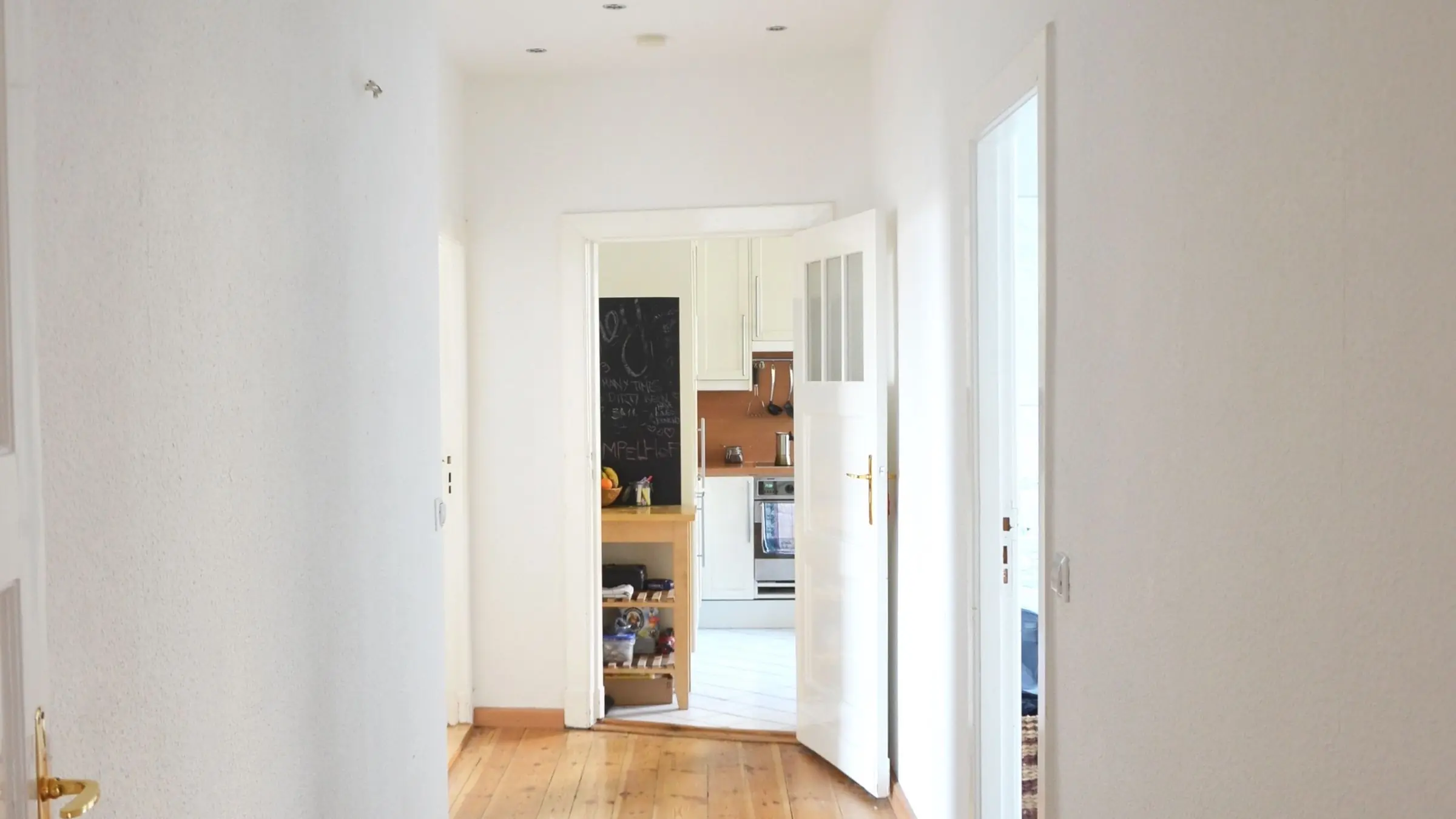 Pasillo de una vivienda con suelo de madera y las puertas abiertas